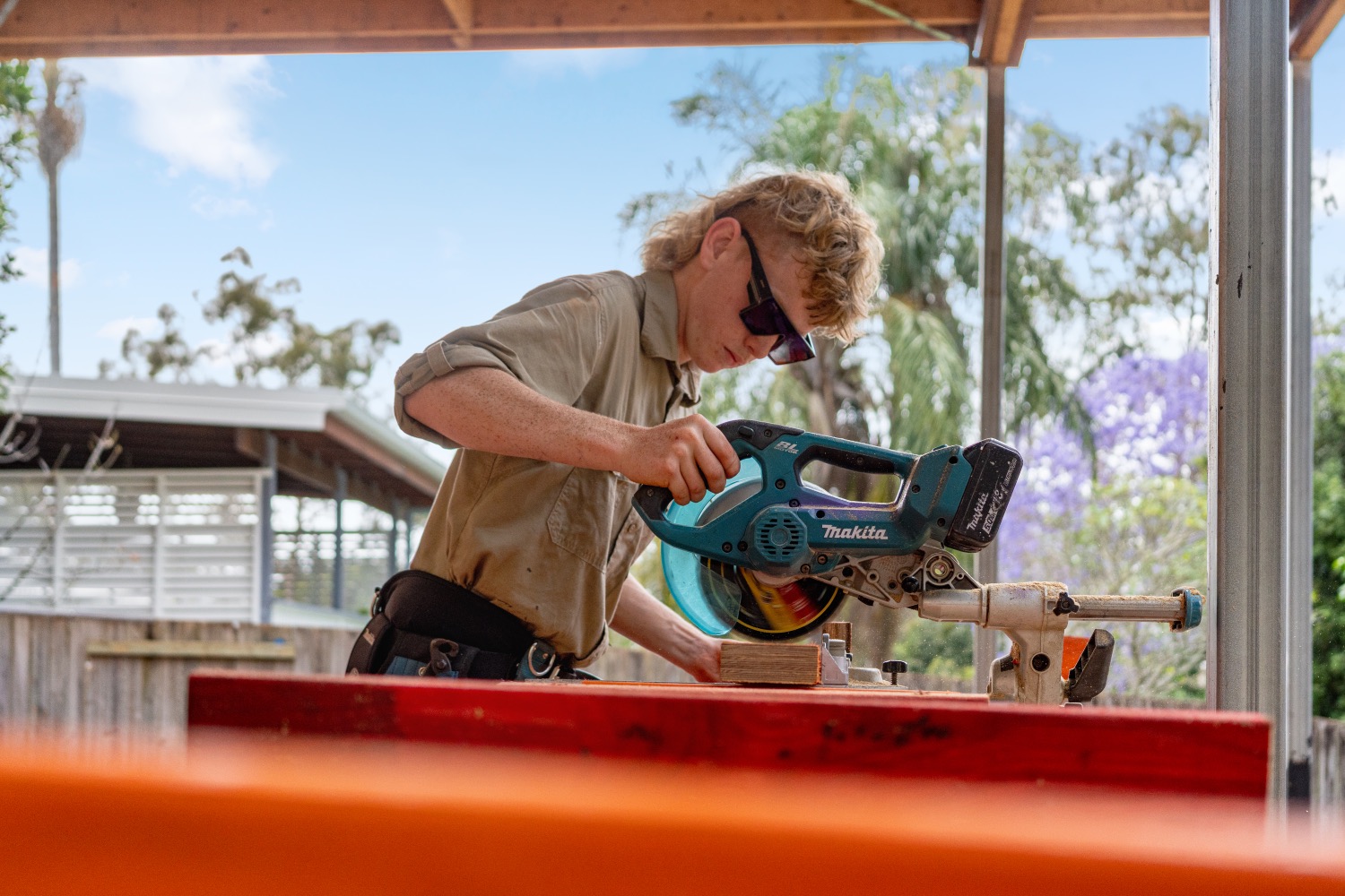 A carpenter cutting framing timber on a mitre saw