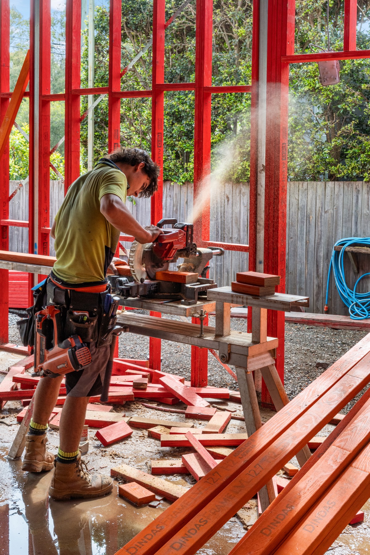 A carpenter cutting framing timber, sawdust in the light